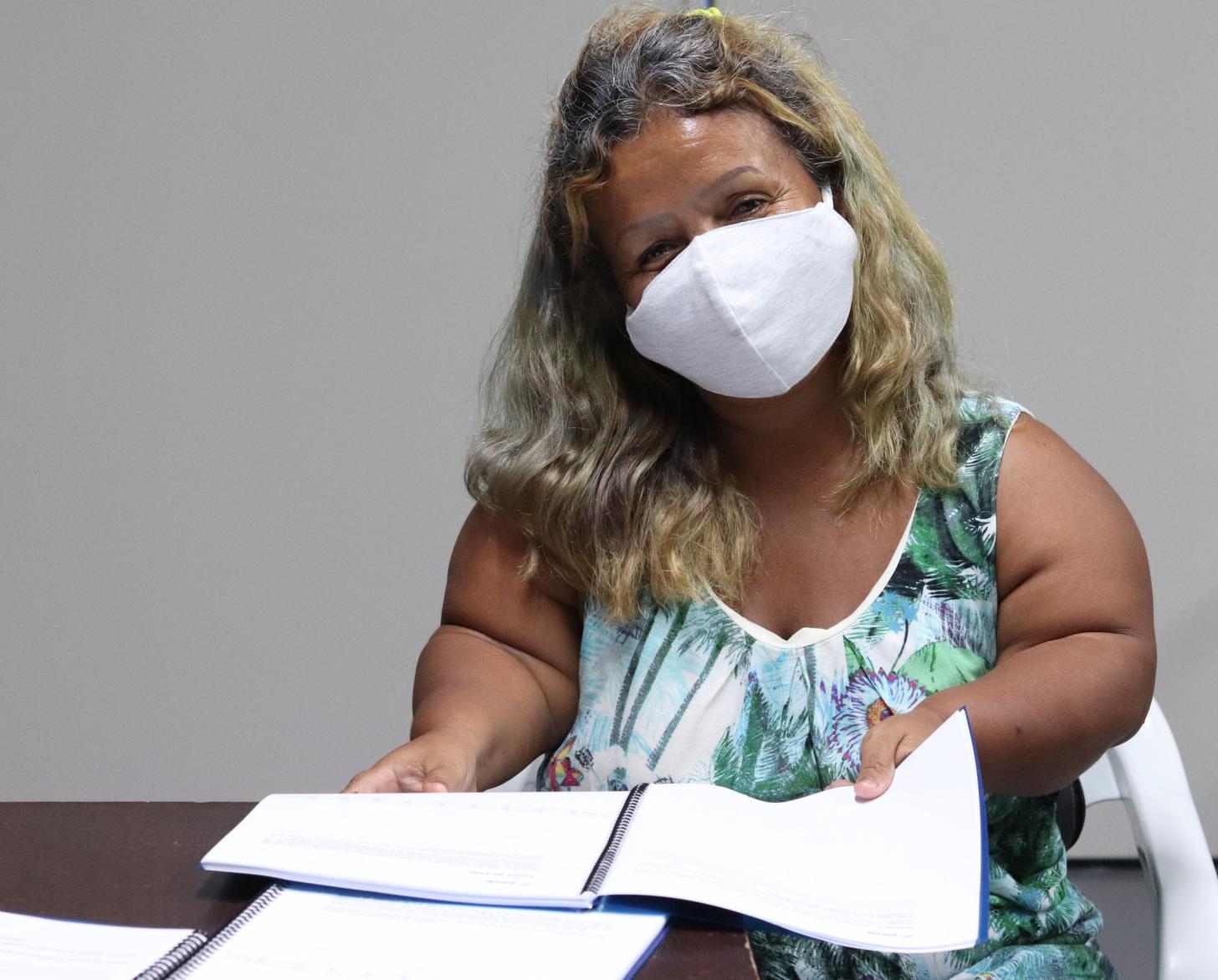 Carmen Bermúdez, de 50 años, sonríe detrás de su mascarilla mientras se sienta con los documentos de capacitación.