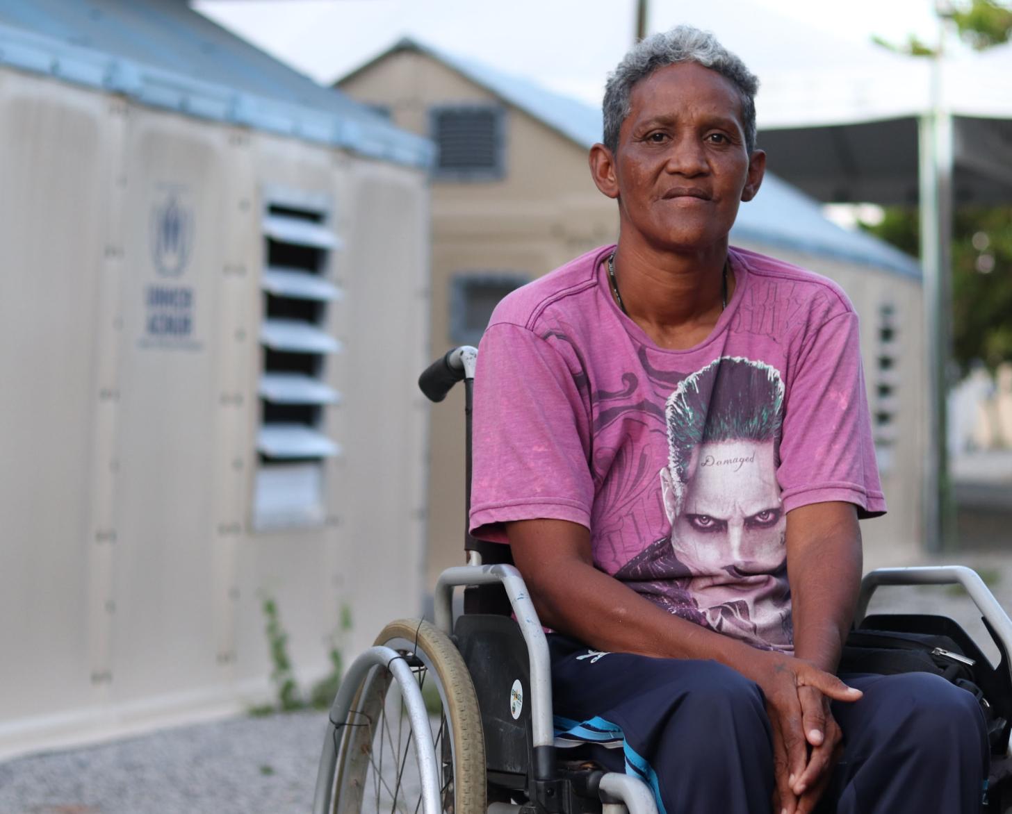 Una mujer sentada en su silla de ruedas fuera del centro de formación.