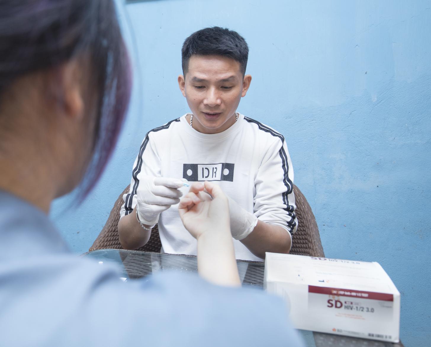 يقدم نجوين ترونج هونغ فحصًا لفيروس نقص المناعة البشرية لأحد زبائنه في مقهى هونغ.