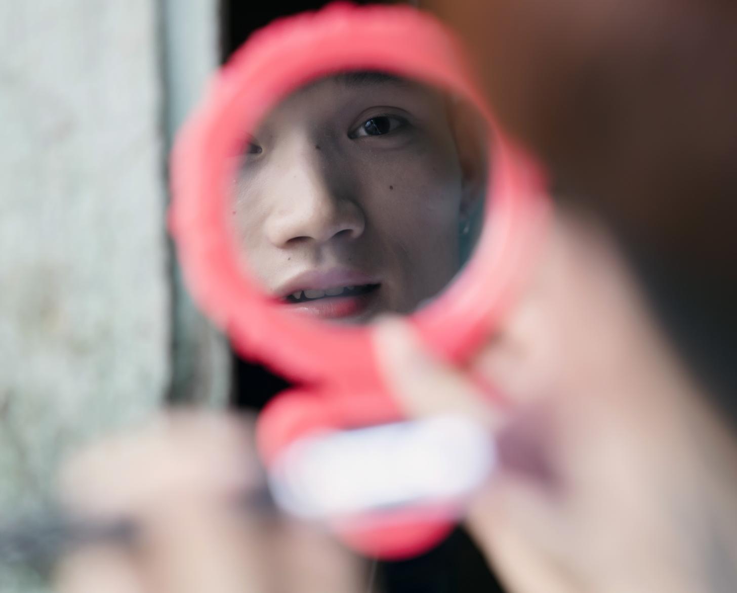 Bui Thi Chi looks at her reflection in a pocket mirror.