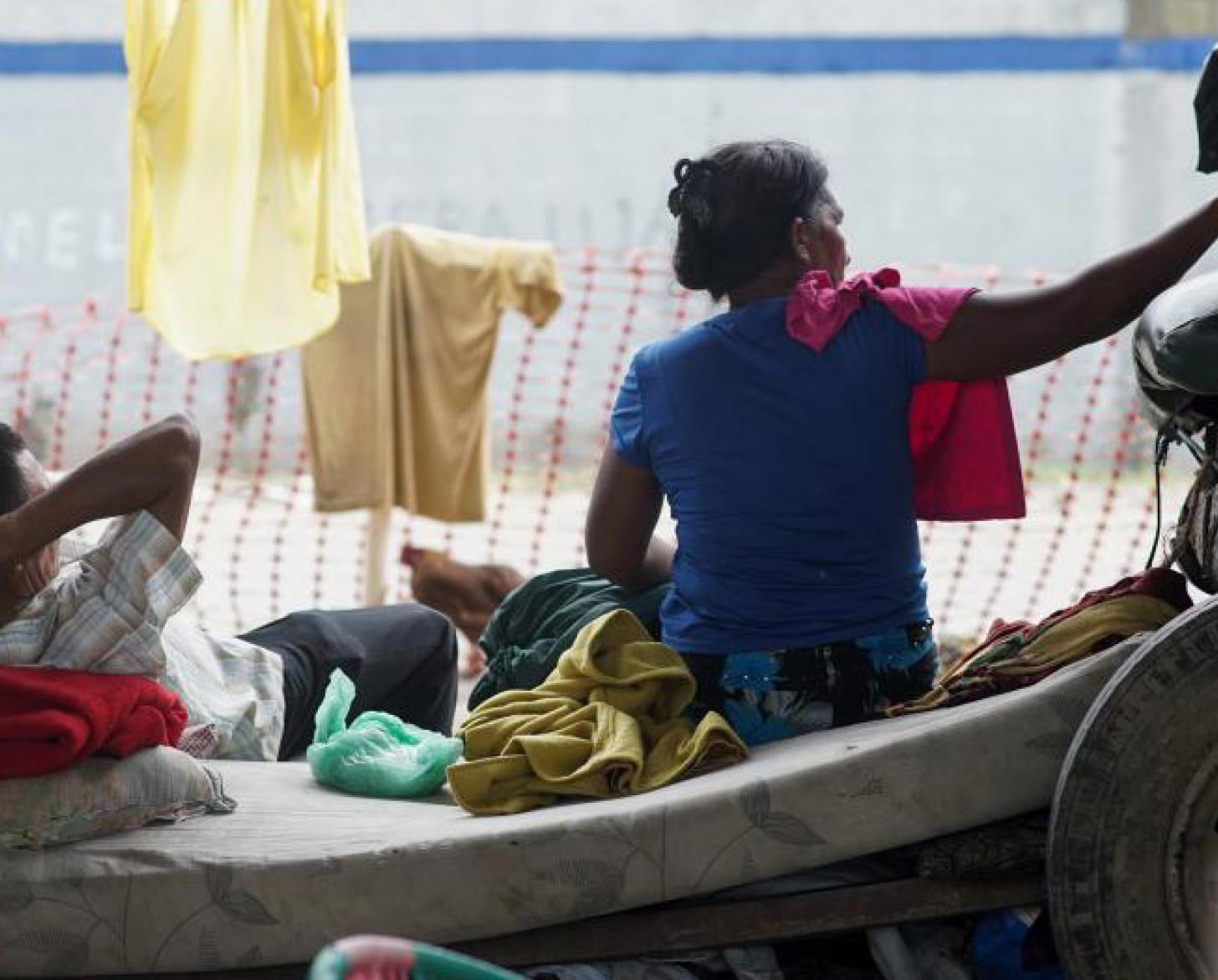 Un homme est à moitié allongé sur un matelas à gauche de l’image. Une femme est assise à sa droite. On leur a porté secours lors de la tempête tropicale qui a frappé le Honduras.