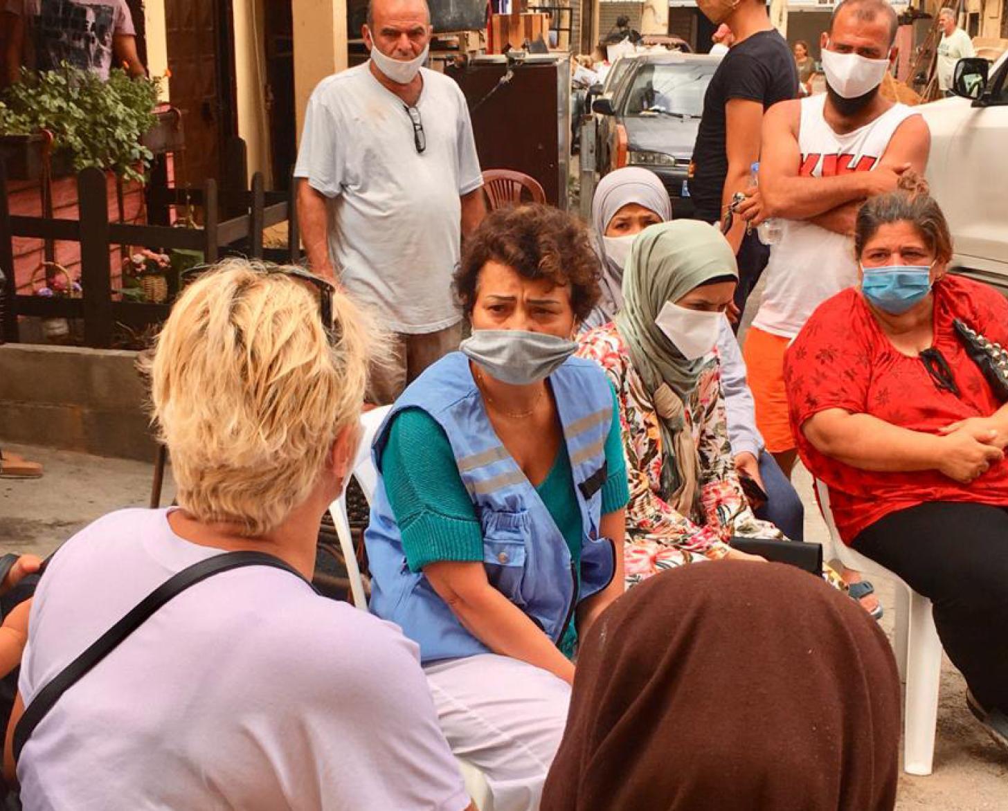 Najat Rochdi sits in between a group of women and men at one of the hardest hit neighbourhoods.
