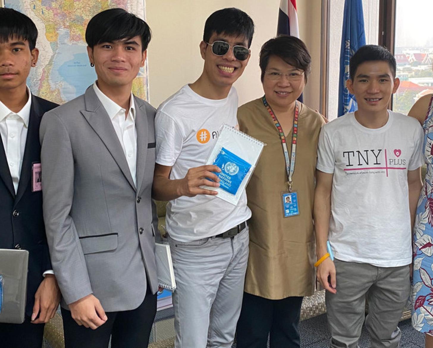 4 hombres jóvenes y dos mujeres sonriendo a la cámara con portátiles y computadoras.