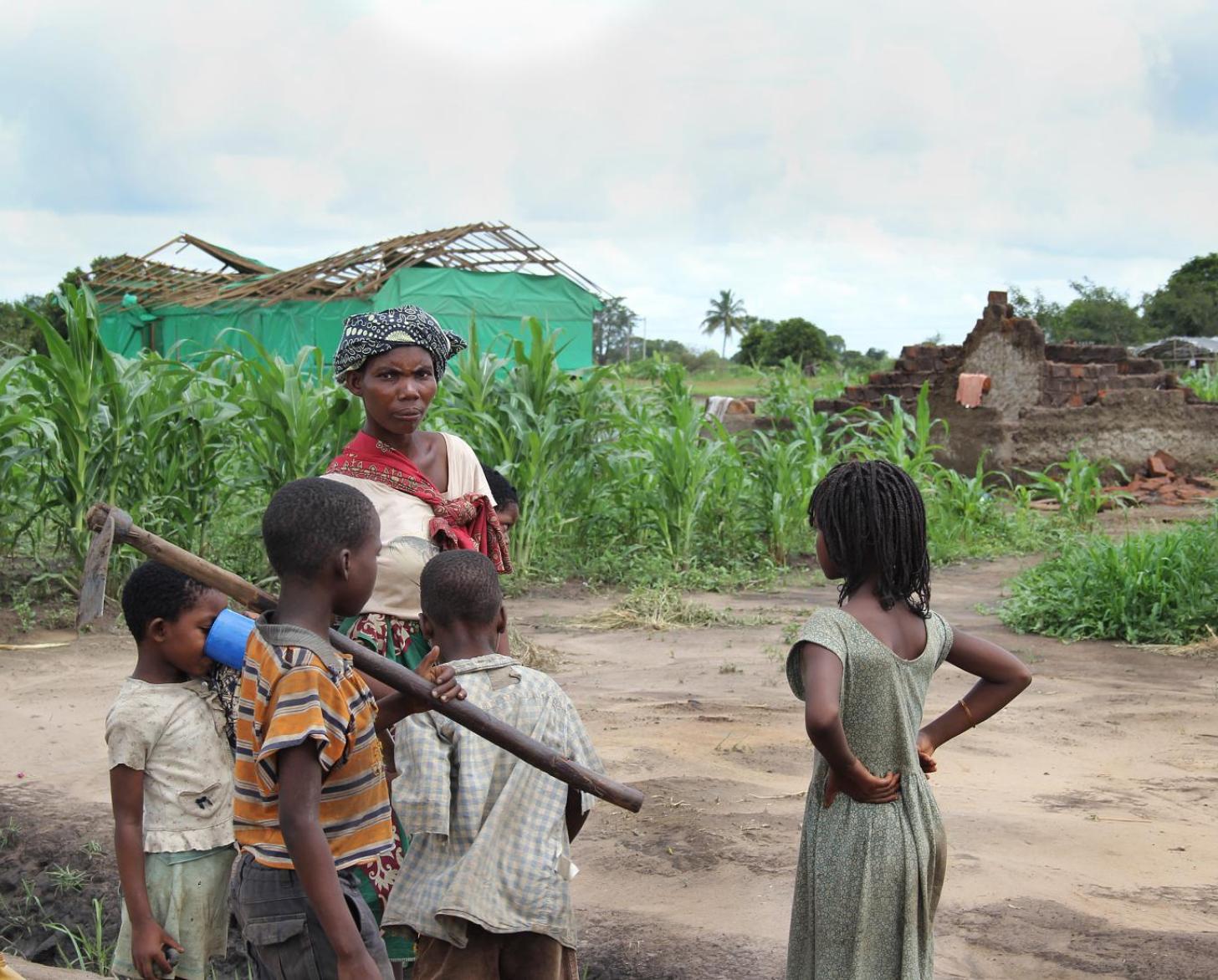 أم مع أطفالها تقف في الخارج بجانب حقولهم بعد إعصار ألويس.