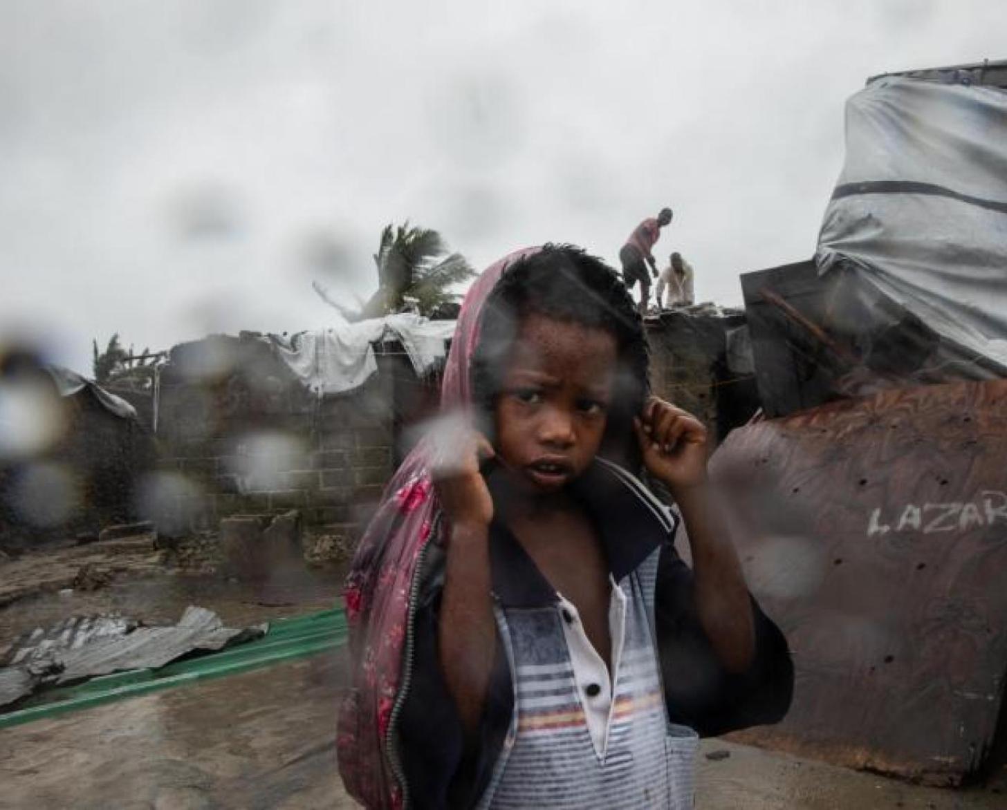 طفل صغير يغطي رأسه بمعطف كي لا يبتل من المطر.