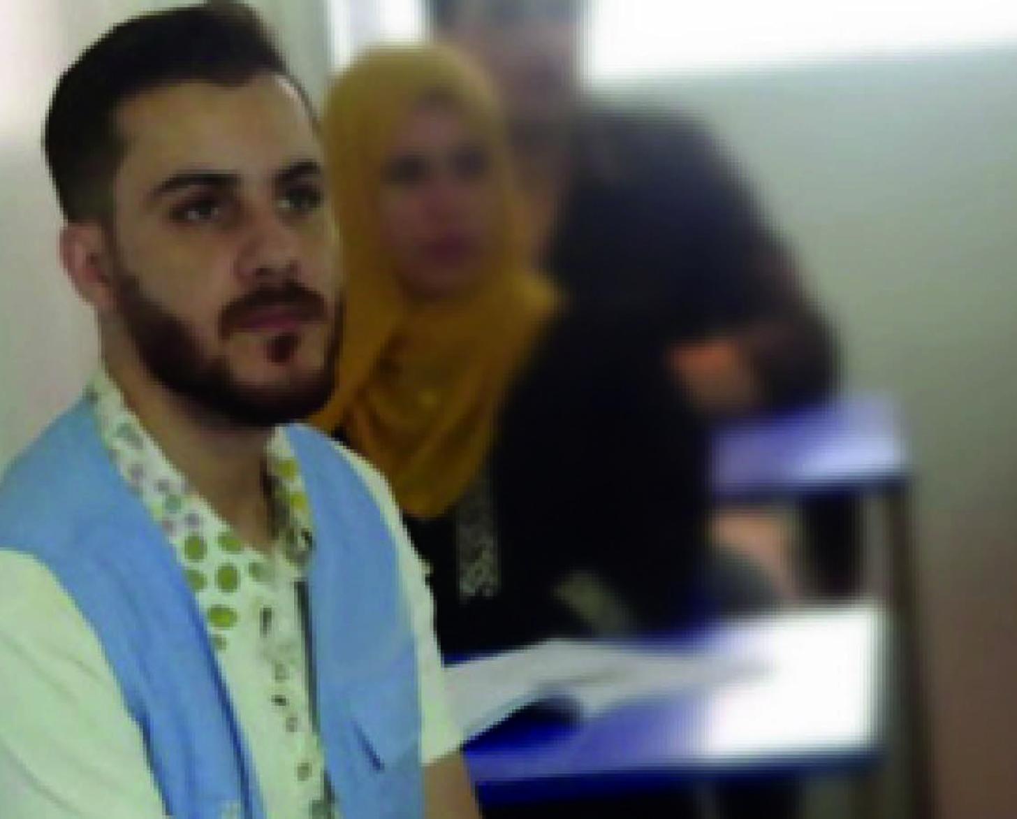 Mohammad sits at his desk in a classroom as he listens to his instructor. 