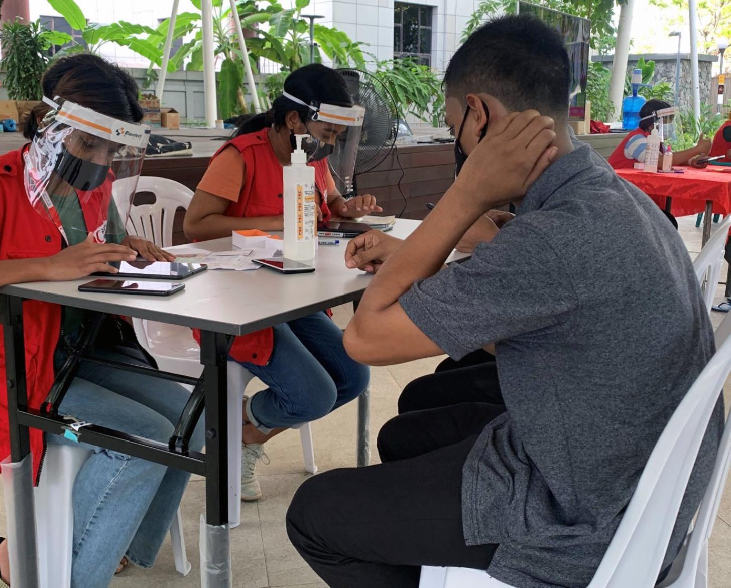 A man sits at a vaccine registration table to check in for his vaccination.