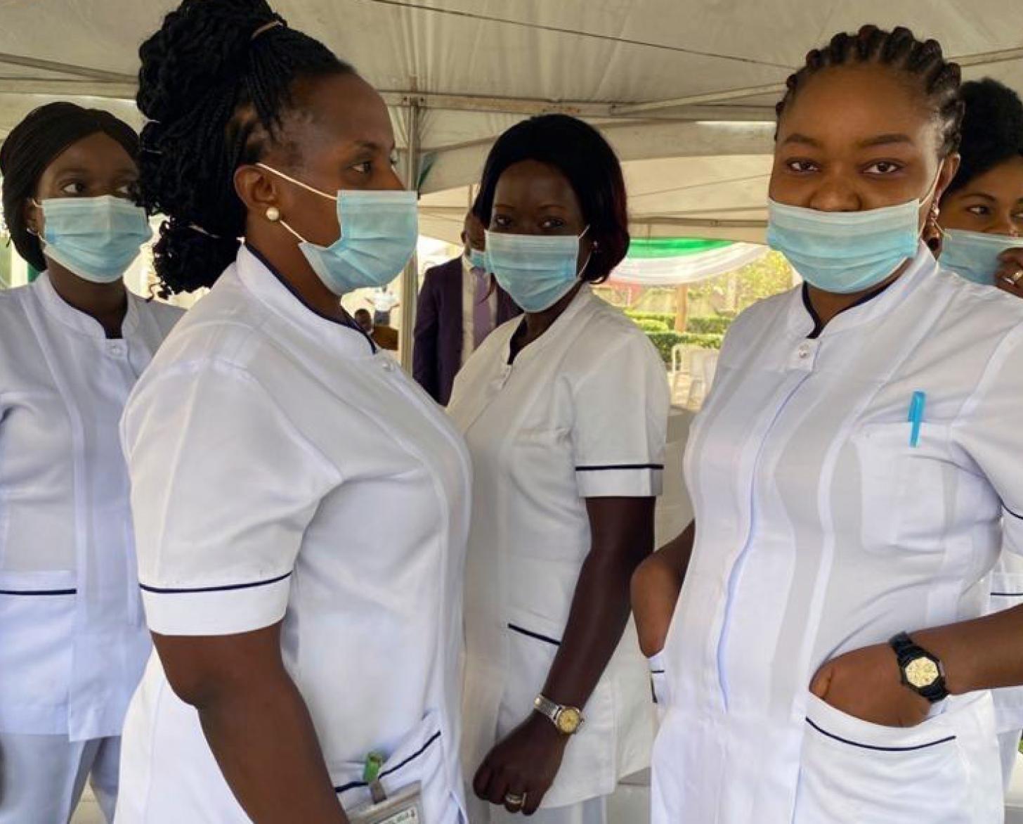 Healthcare workers wearing face masks stand together underneath a tent.