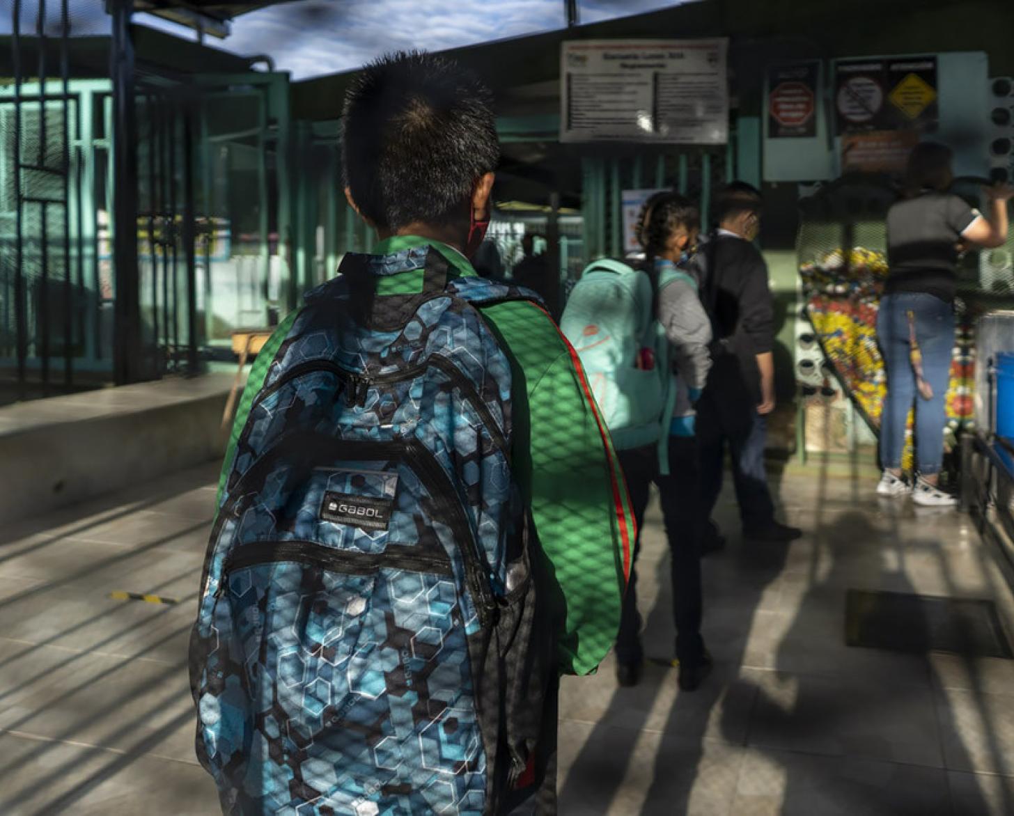 يقف الأطفال في طابور حاملين حقائب الظهر وهم على استعداد للعودة إلى المدرسة.