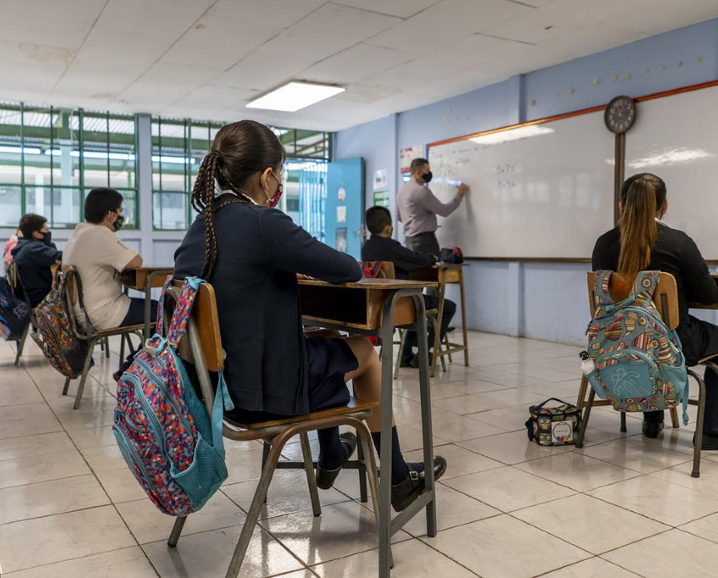 تلاميذ يرتدون كمامات ويجلسون على مقاعد داخل الصف.