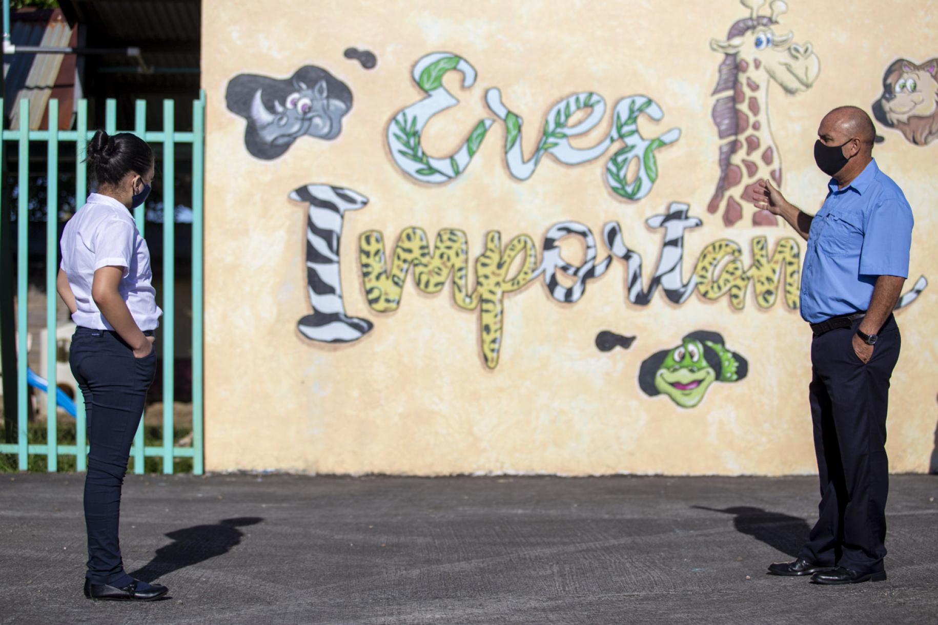 ينظر المعلم والطالب إلى شعار المدرسة الذي يقول: "أنت مهم".