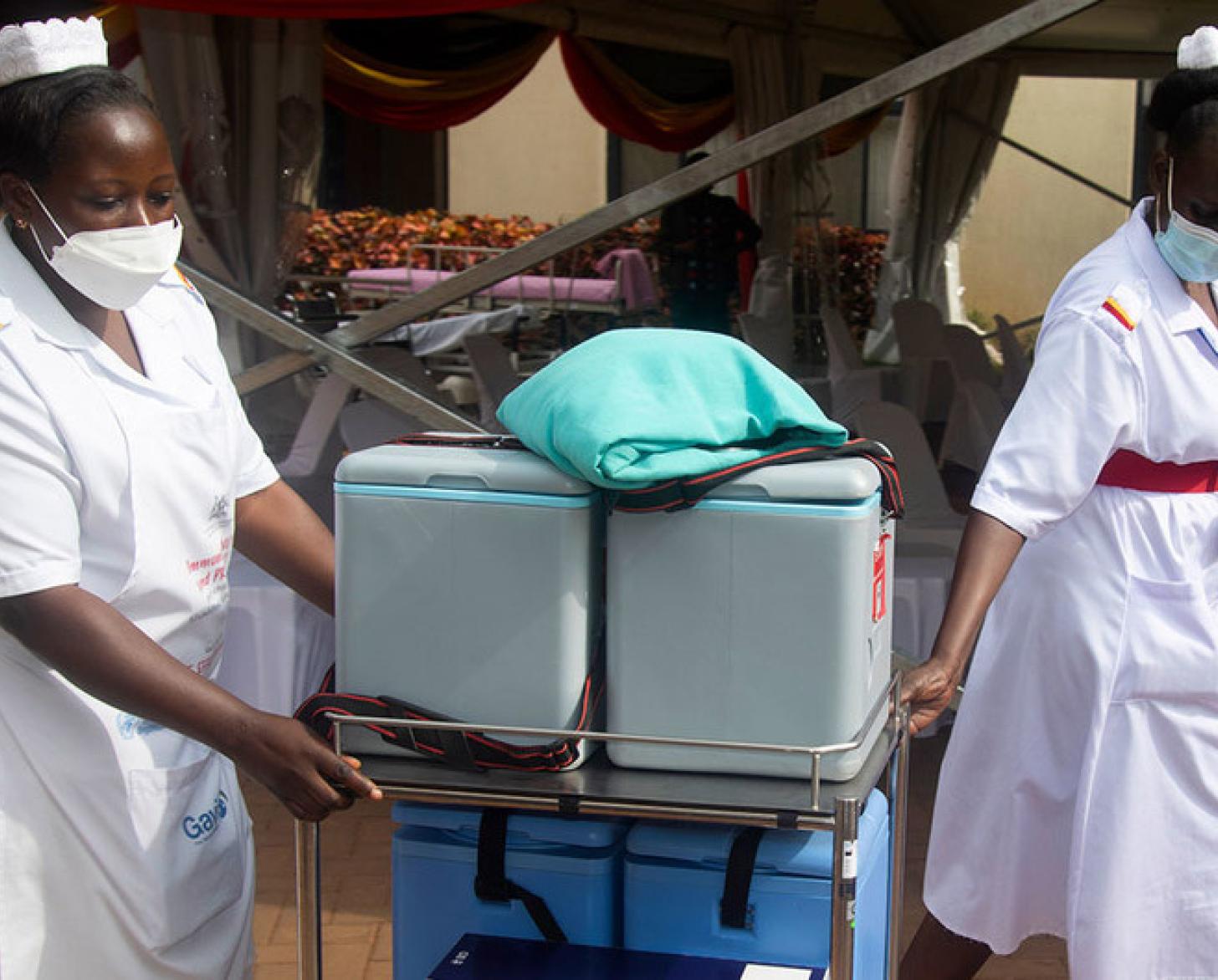 Two women in medical outfits cart around medical supplies. 
