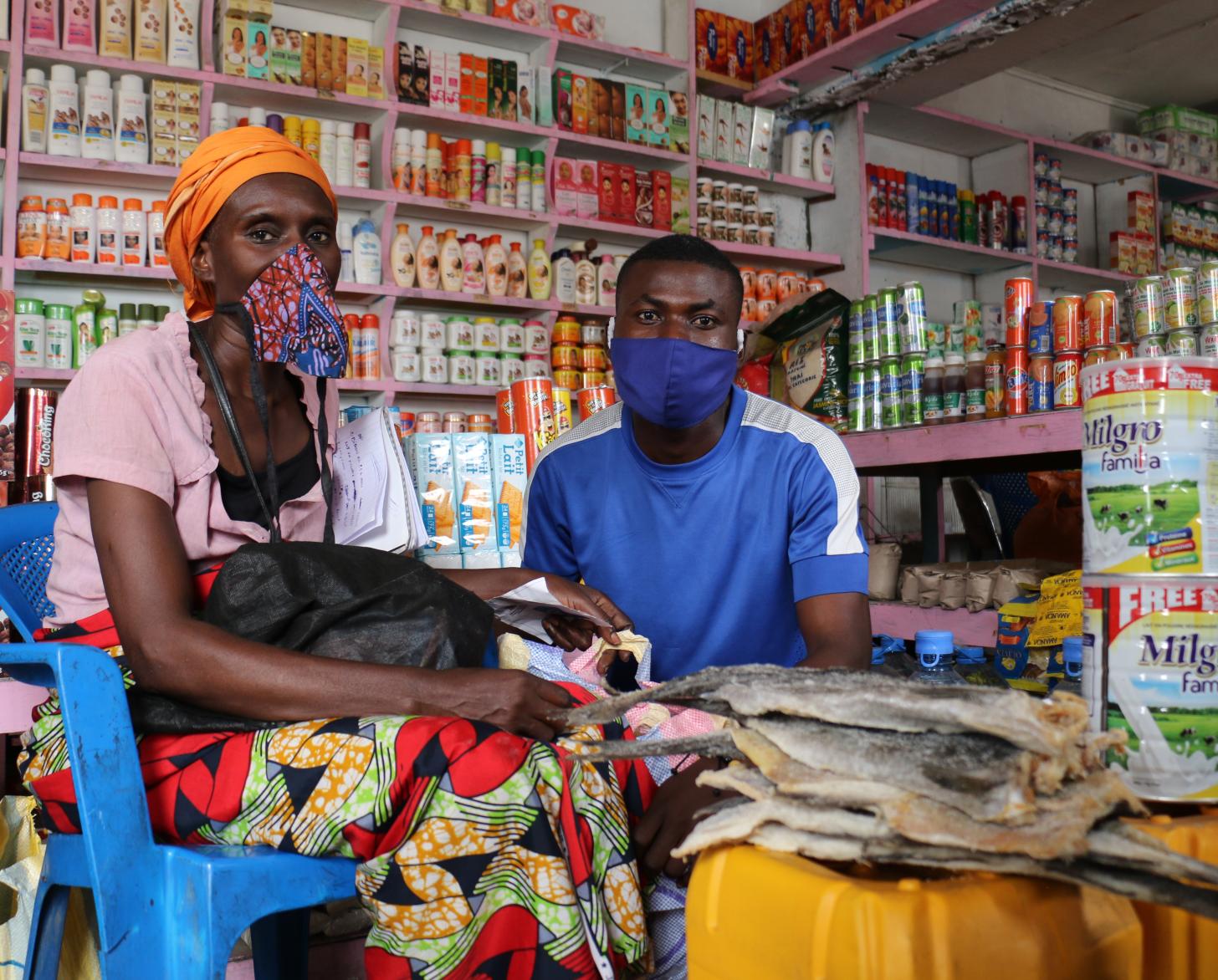 A woman and man wearing face mask sit inside their local market.