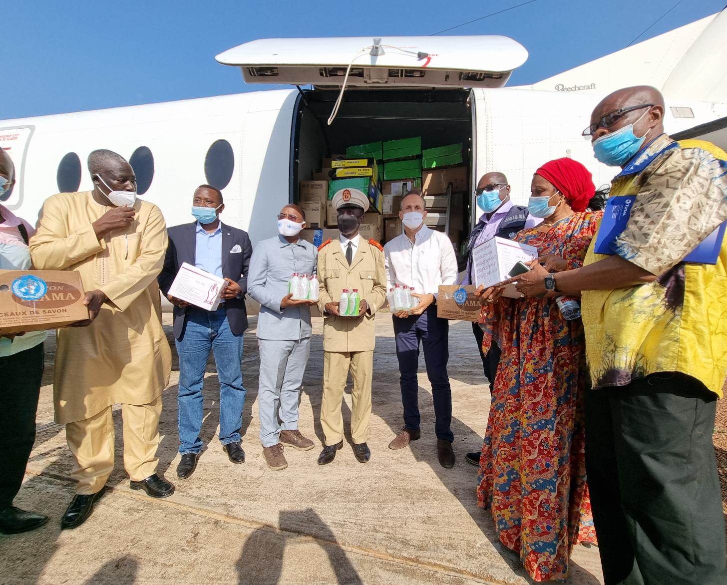 يقف عدد من الأشخاص على شكل نصف دائرة بجوار طائرة.