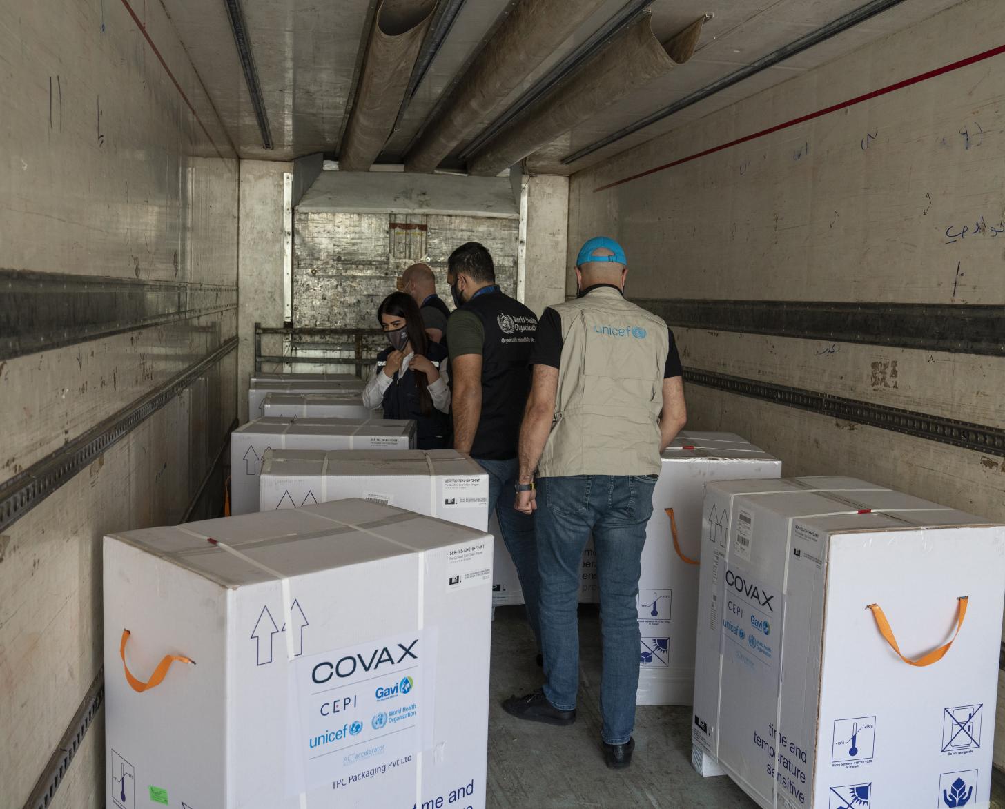 أفراد فريق الأمم المتحدة القطري يتفقدون شحنة لقاحات في شاحنة مبردة وصلت إلى سوريا.