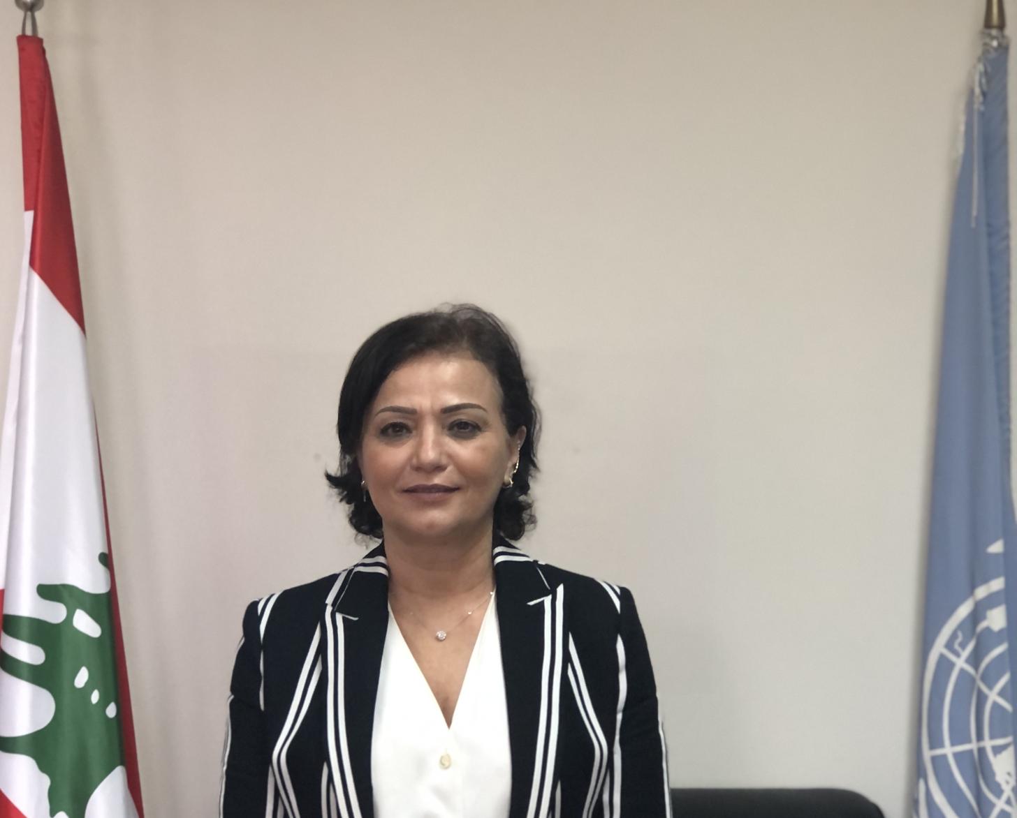 Una imagen de Najat Rochdi de pie entre dos banderas.