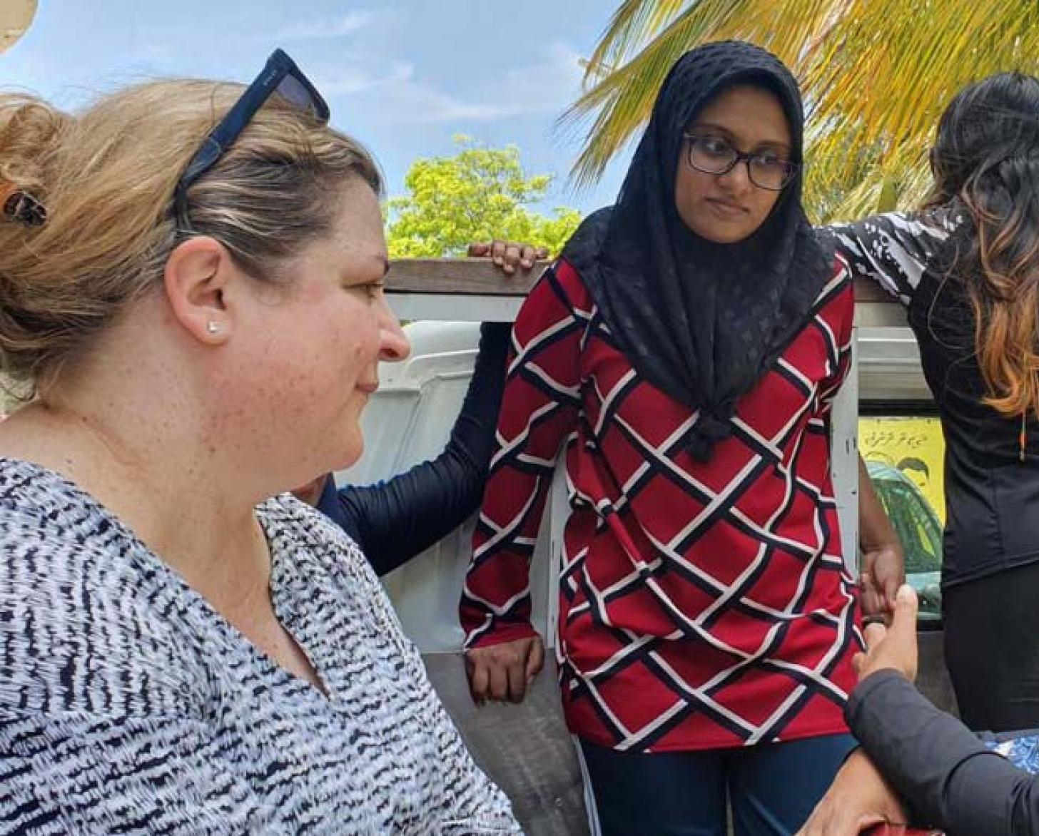 Trois femmes, dont la Coordonnatrice résidente aux Maldvies, Catherine Haswell, discutent à l'extérieur.