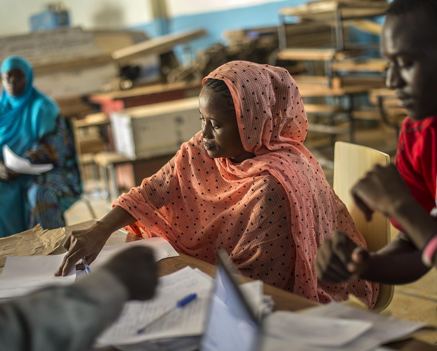 Cuatro personas, juntas, rellenan el papeleo sobre los escritorios.