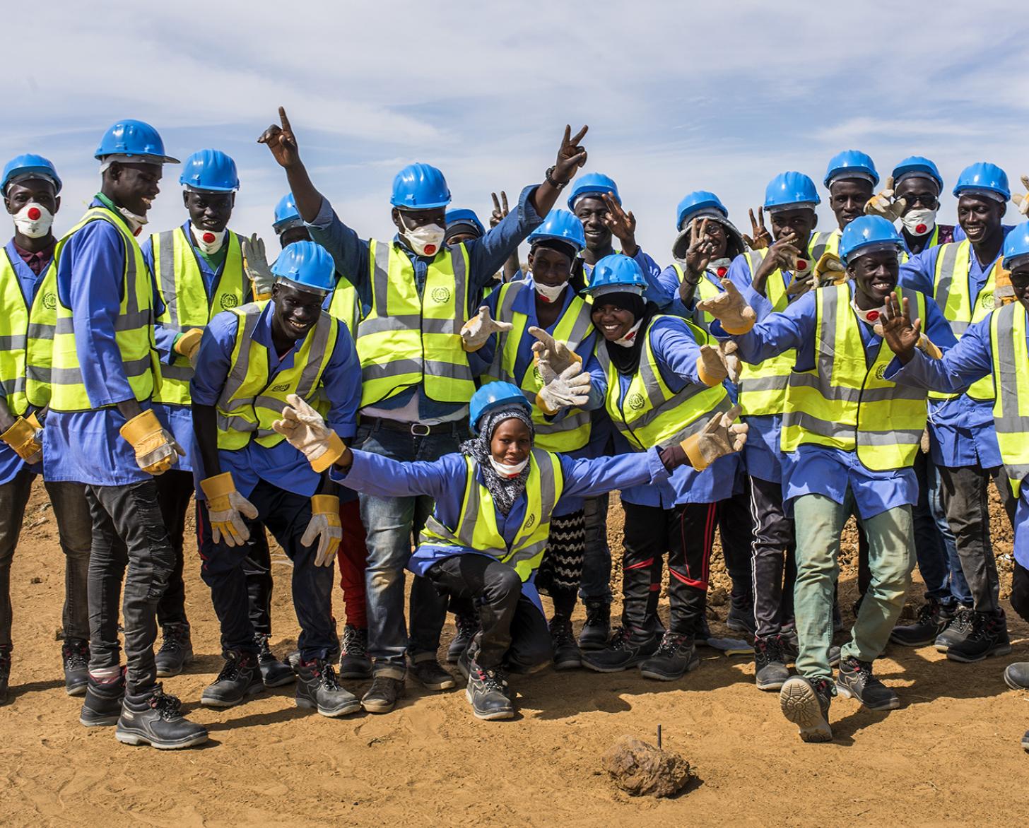 Un grupo de trabajadores de la construcción sonríe ampliamente a la cámara.