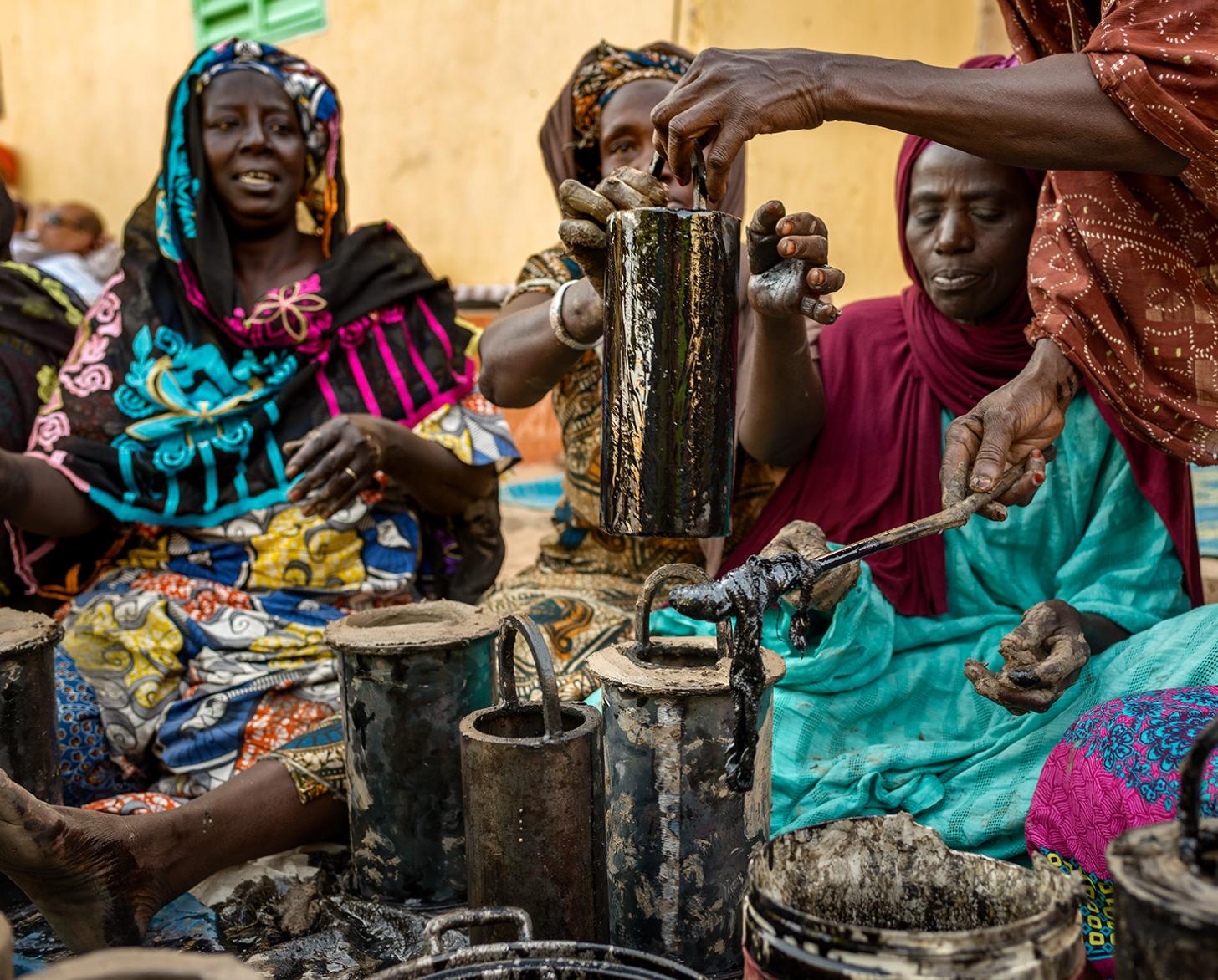 Un grupo de mujeres vestidas de forma brillante se sientan juntas con pipas.