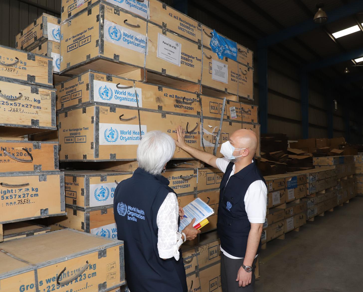 شخصان يفحصان شحنة كبيرة من المستلزمات الطبية.