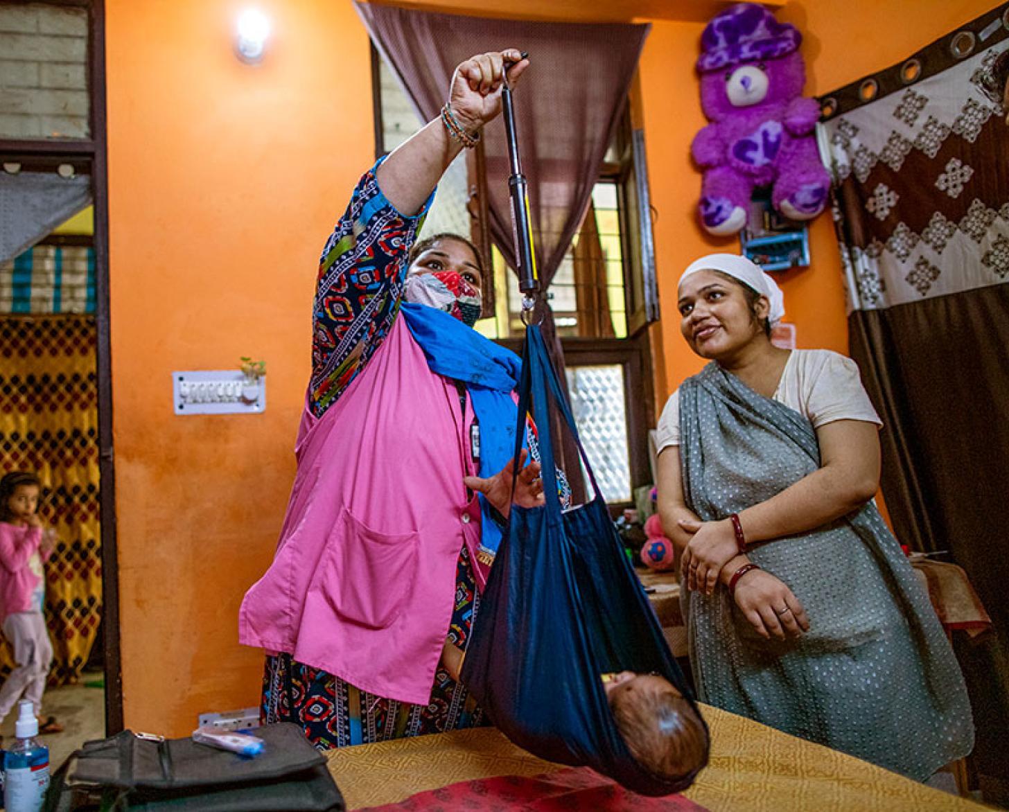 امرأتان تزنان طفلًا داخل المنزل.