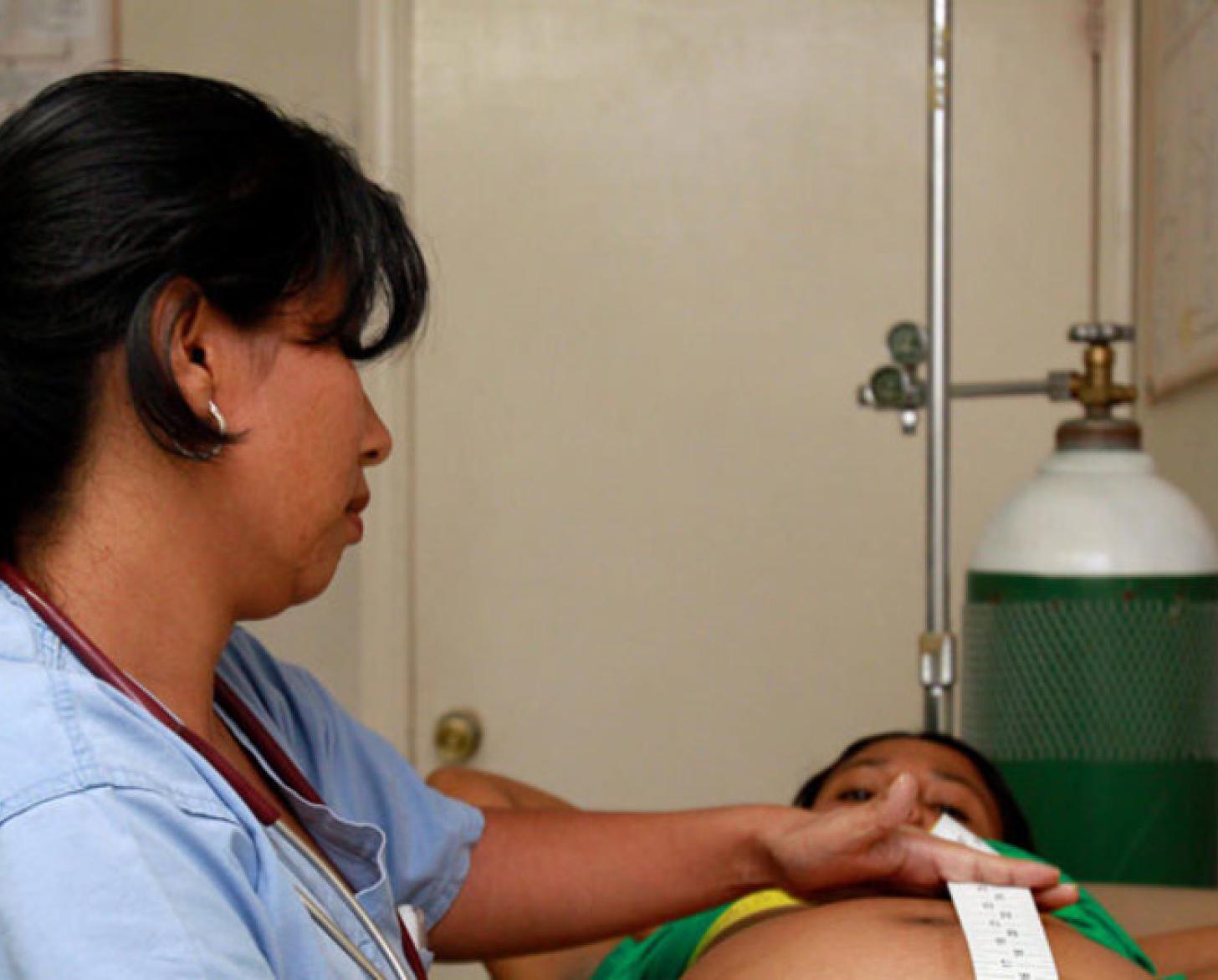 Une professionnelle de santé portant une queue de cheval s'occupe d'une femme enceinte dans un établissement de santé.