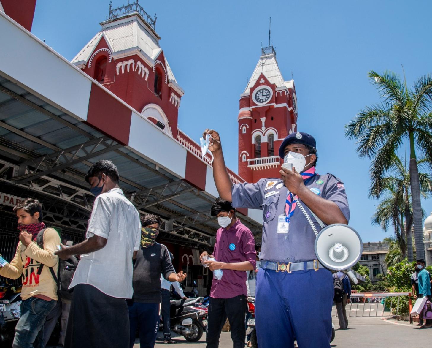 رجل يتحدث مستخدمًا البوق خارج مبنى أحمر في يوم جميل.