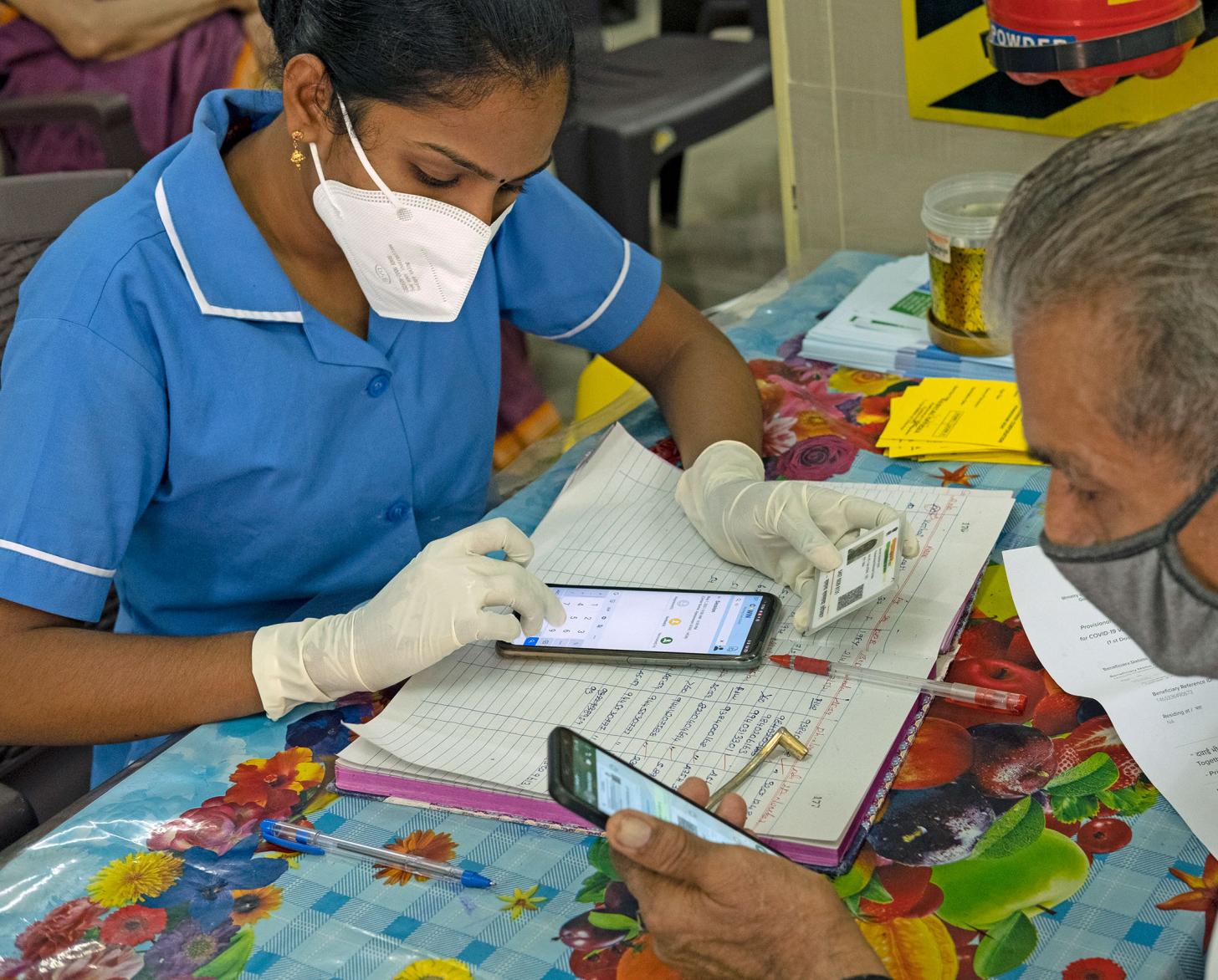 امرأة تستخدم هاتفًا خلويًا لتسجيل اسم رجل على منصة اللقاحات.