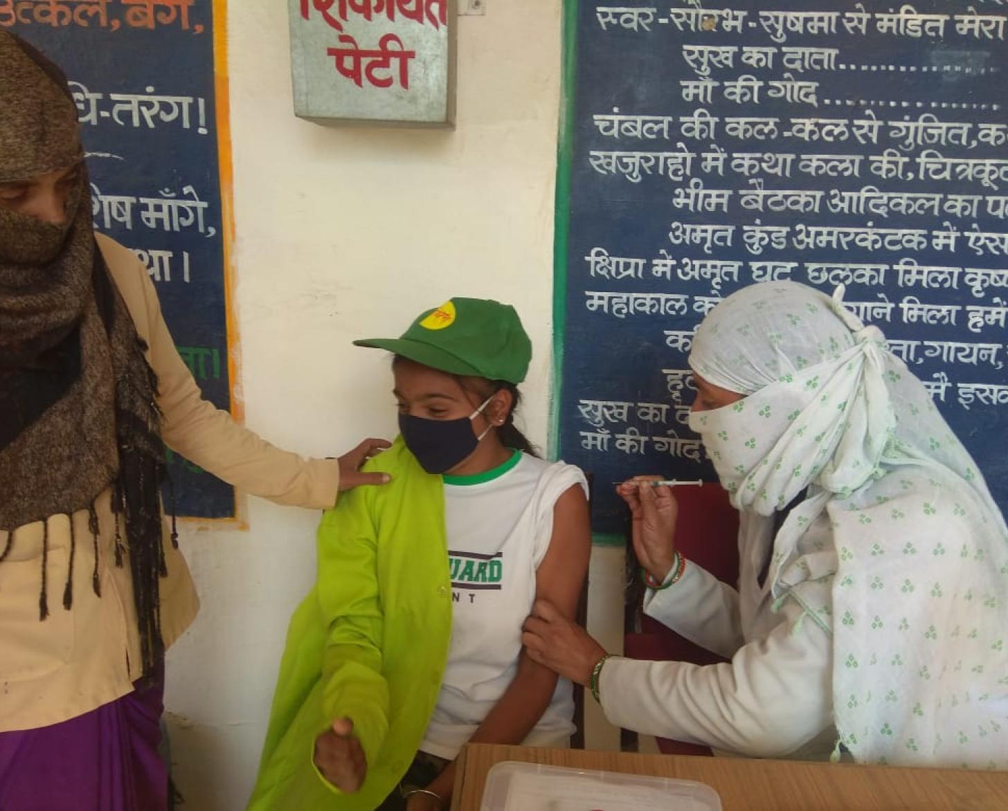 شاب يتلقى لقاح كوفيد-19 داخل المدرسة.