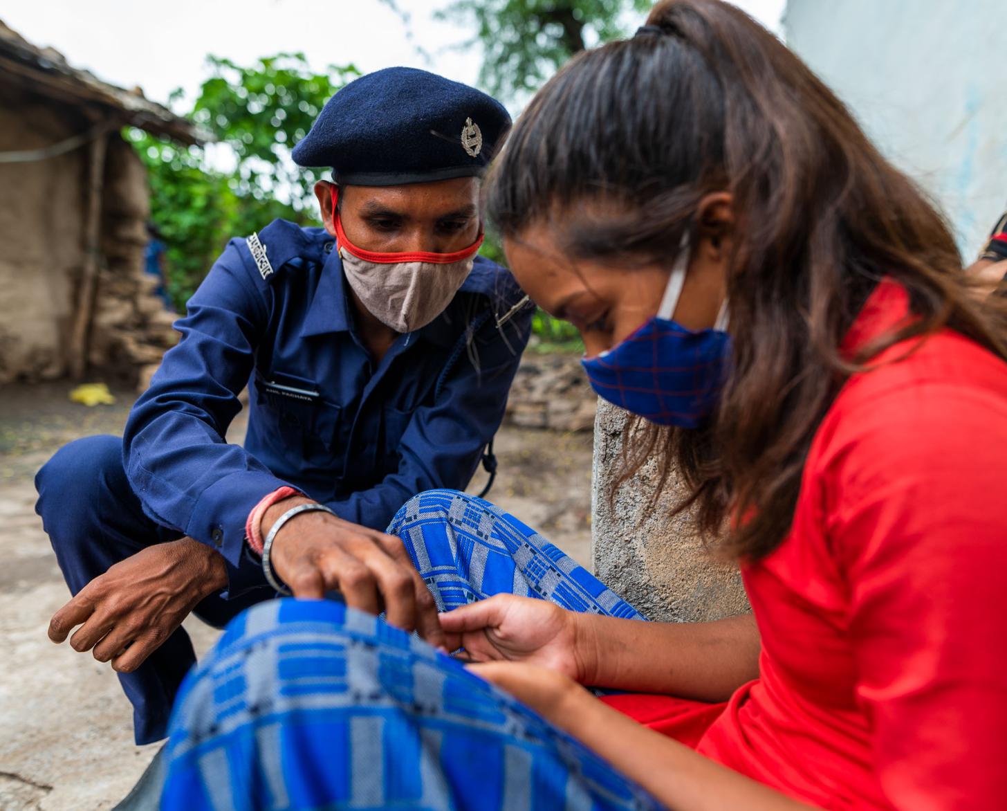 يركع شخص يرتدي زيًا عسكريًا بجانب فتاة تنظر إلى هاتفها.