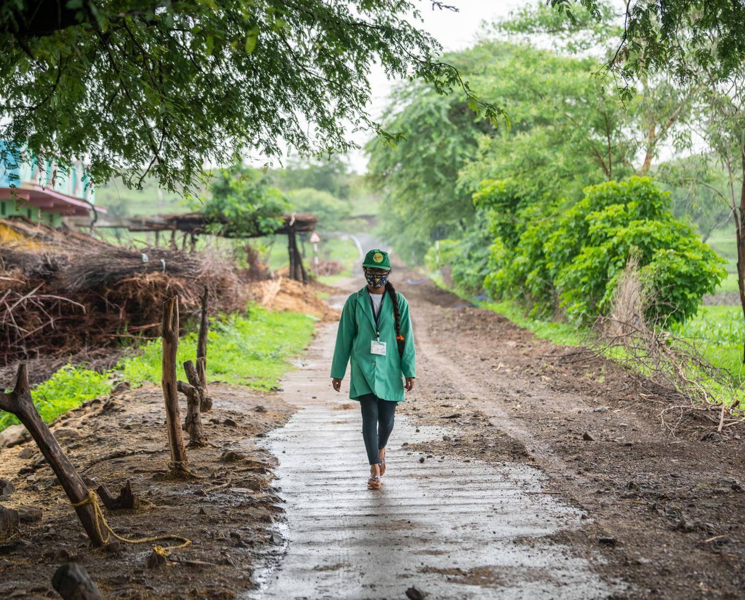 امرأة يرتدي سترة خضراء تسير في طريق موحل.