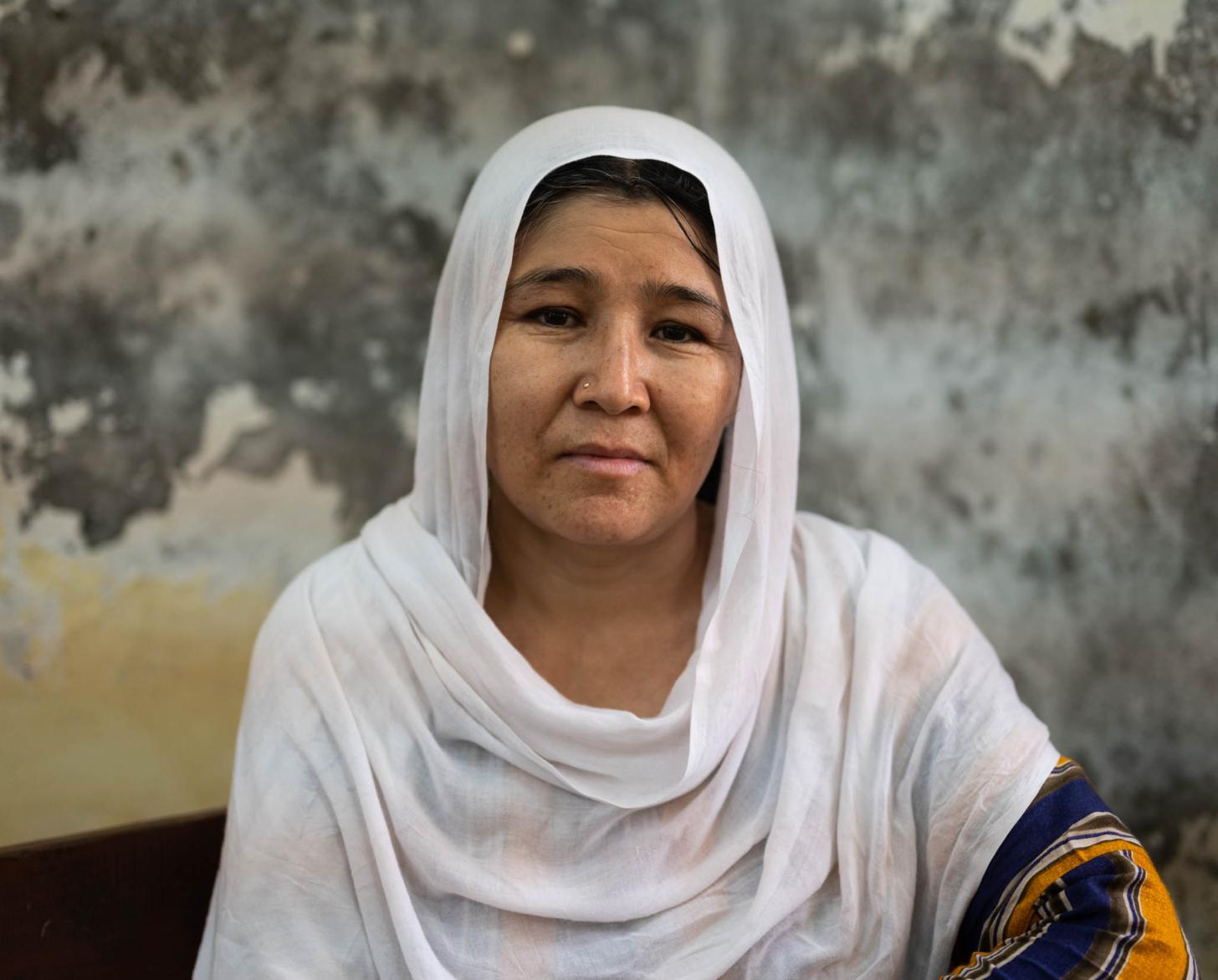 امرأة ترتدي وشاحًا أبيض تنظر مباشرة إلى الكاميرا.