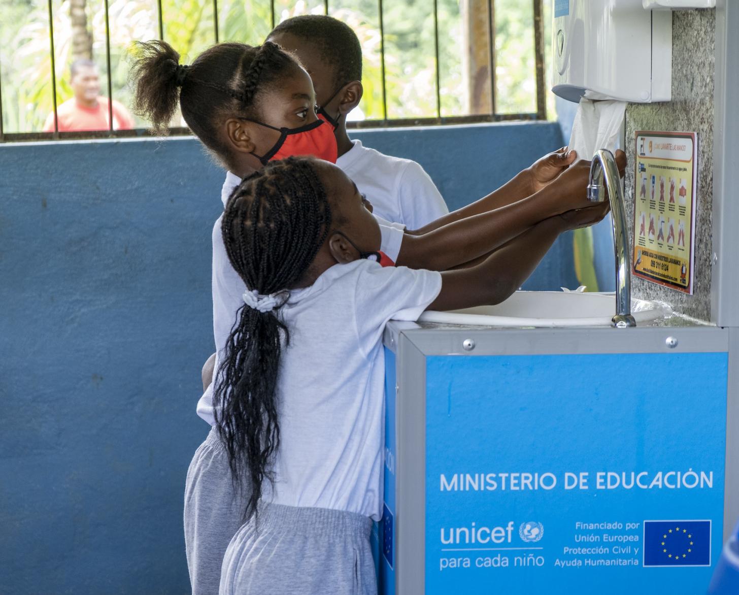 ثلاثة أطفال يغسلون أيديهم في المدرسة.