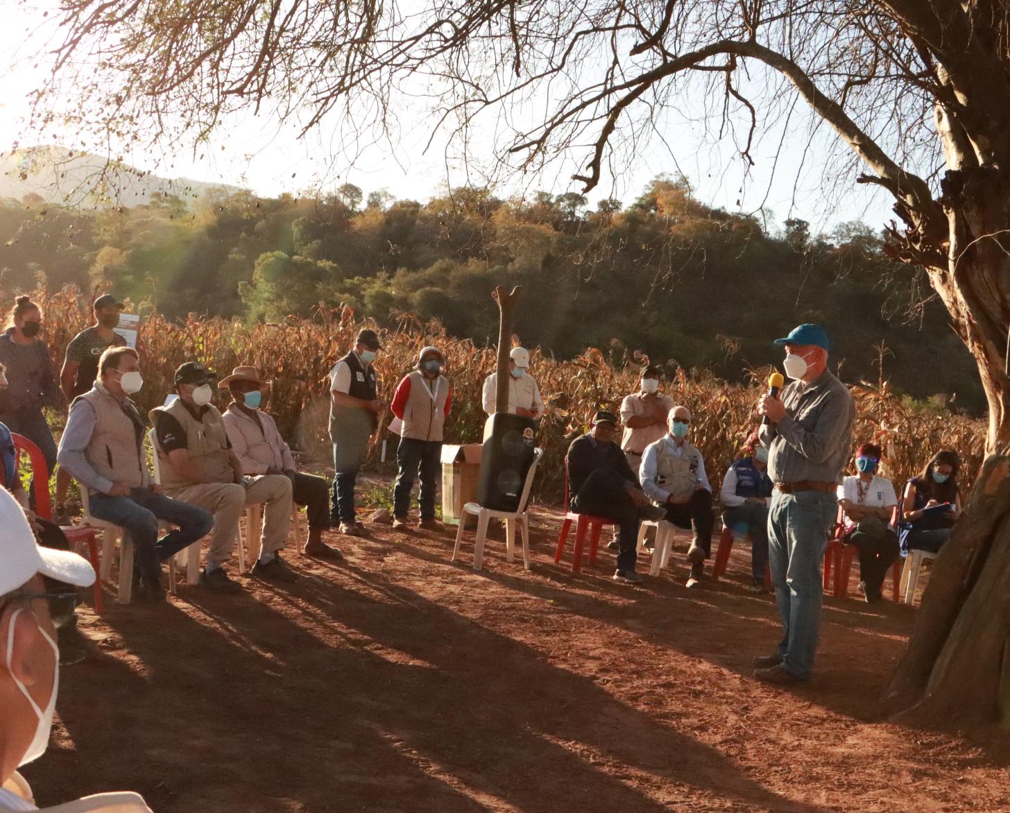 Un grupo de personas en un escampado duranta la visita al centro demostrativo de capacitación de la comunidad Arenal en Bolivia.