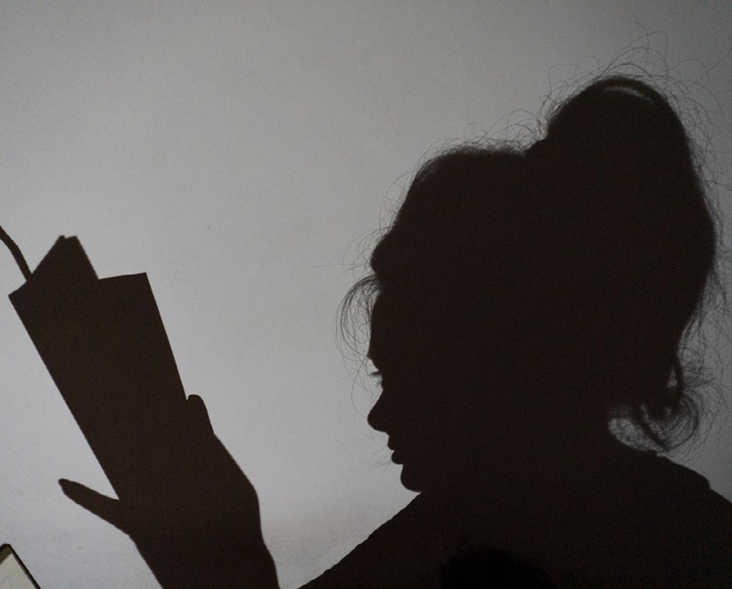 صورة ظلية لامرأة تقرأ كتابًا.