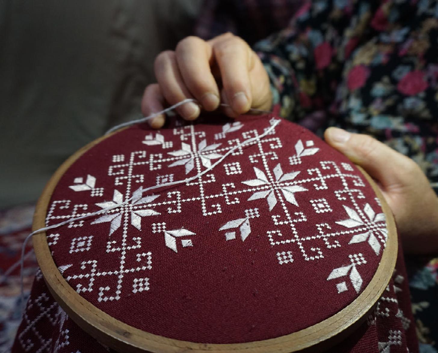لقطة قريبة ليدين تقومان بأعمال تطريز.