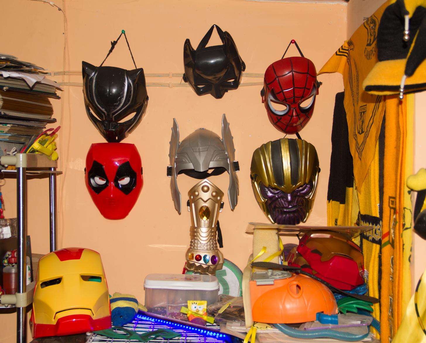 Una pared color melón con una colección de máscaras de superhéroes.