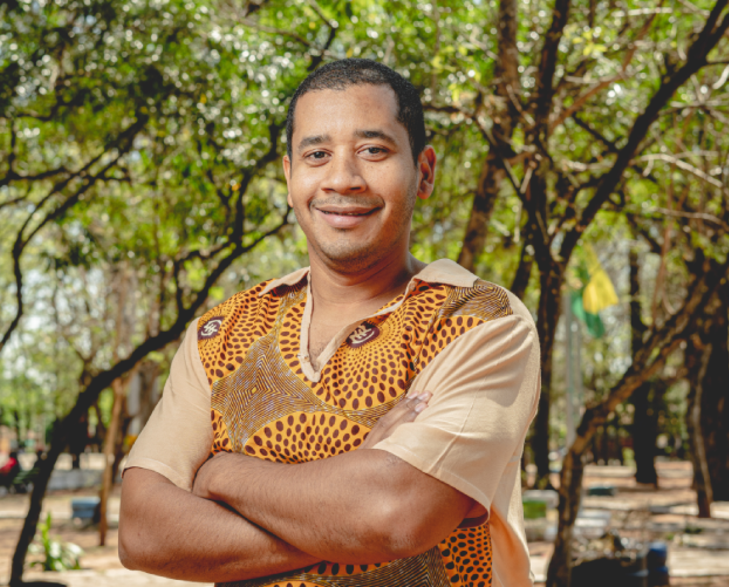 رجل يرتدي قميصًا بلون الخردل يبتسم للكاميرا.