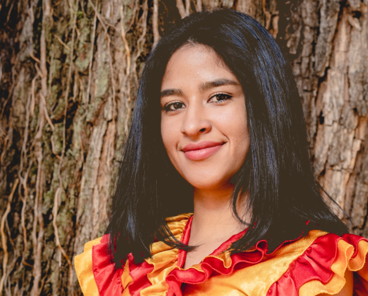 شابة ترتدي قميصًا أحمر وأصفر تبتسم للكاميرا.