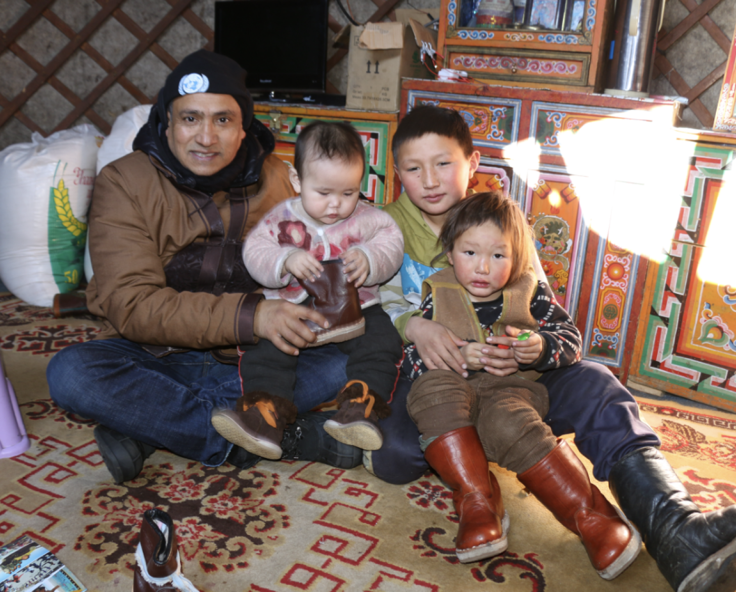 Man sits on carpet with three young children 