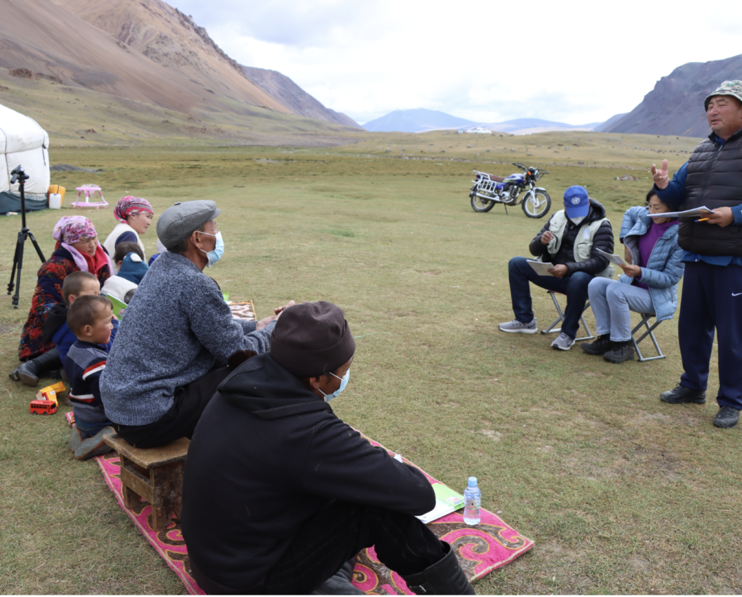 Man speaks to people sitting down on the grass 