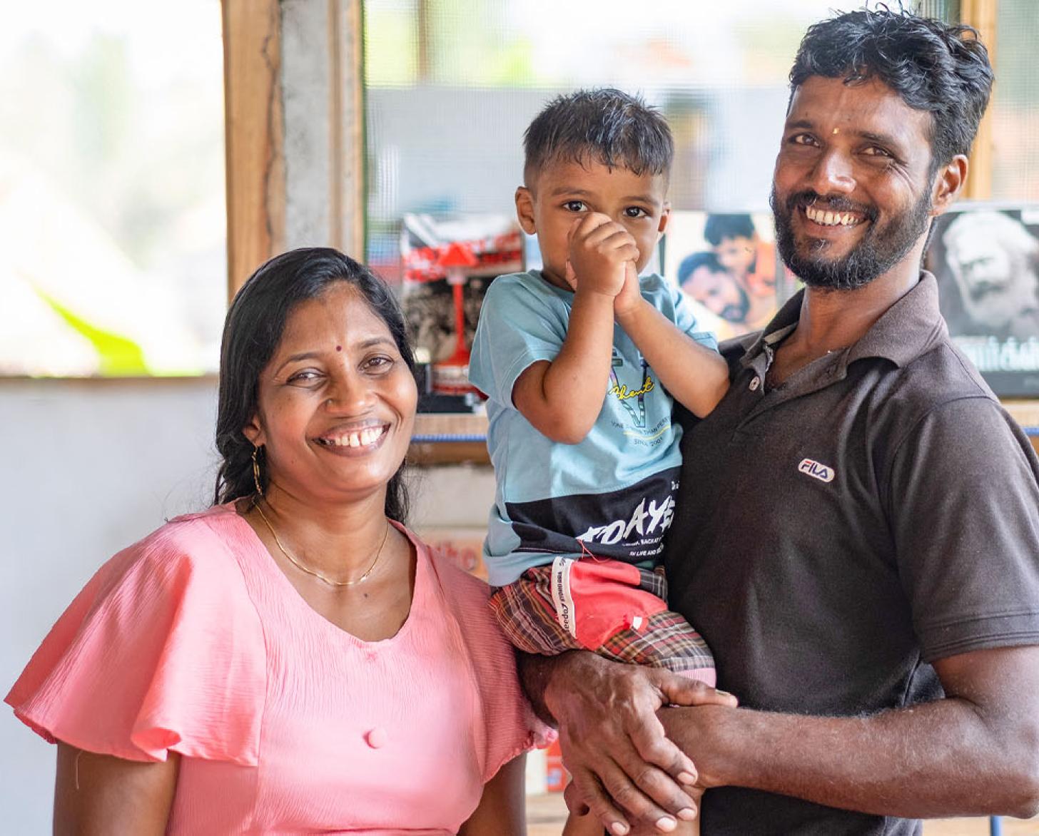 Amother and father with their young son smile for the camera.