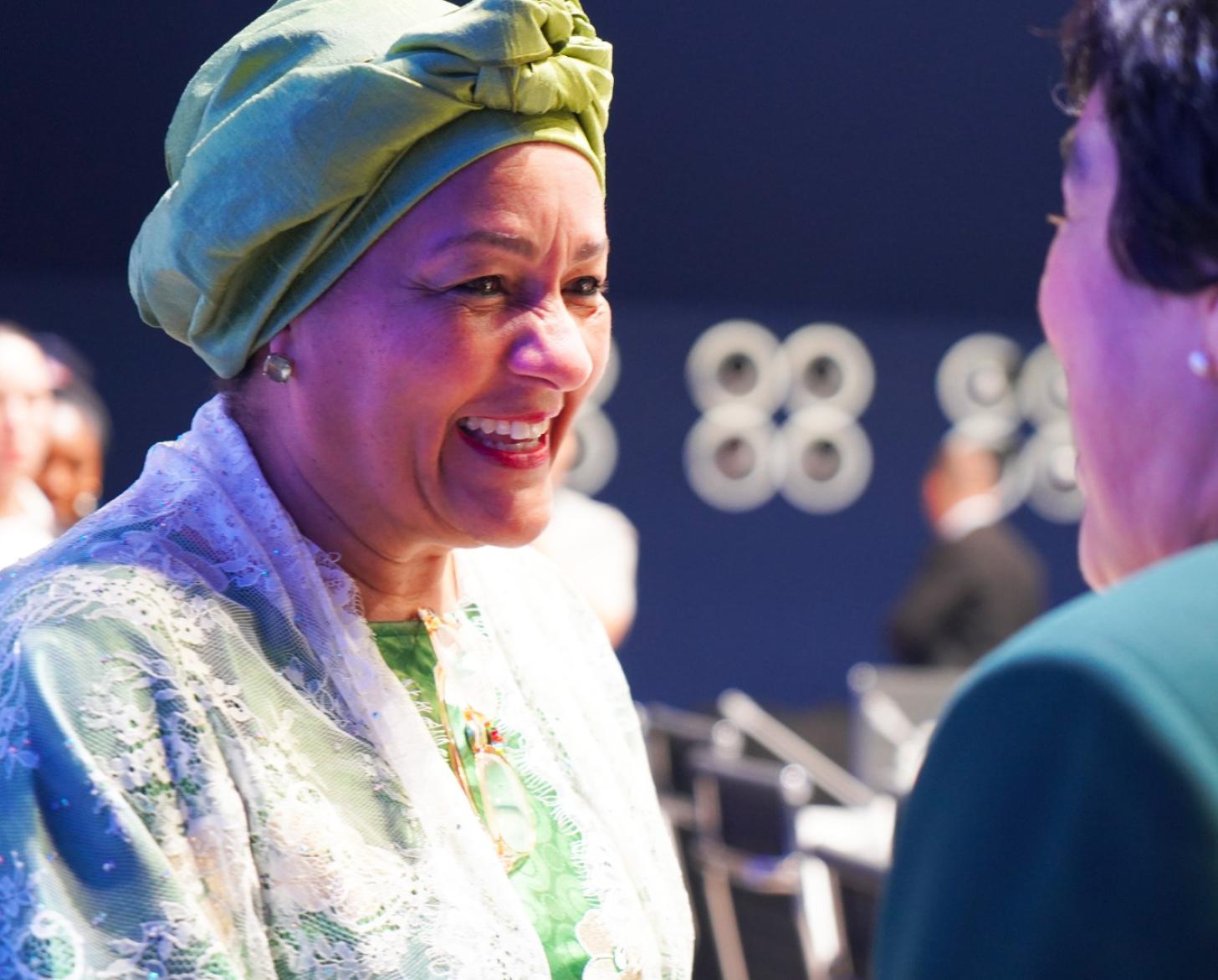 A UN official, the deputy head of the UN, speaks to a member of a partner organization, and smiles brightly.