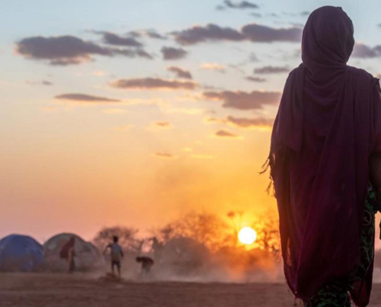 Фотография женщины и маленького мальчика, на фоне закатного солнца, в лагере для беженцев.
