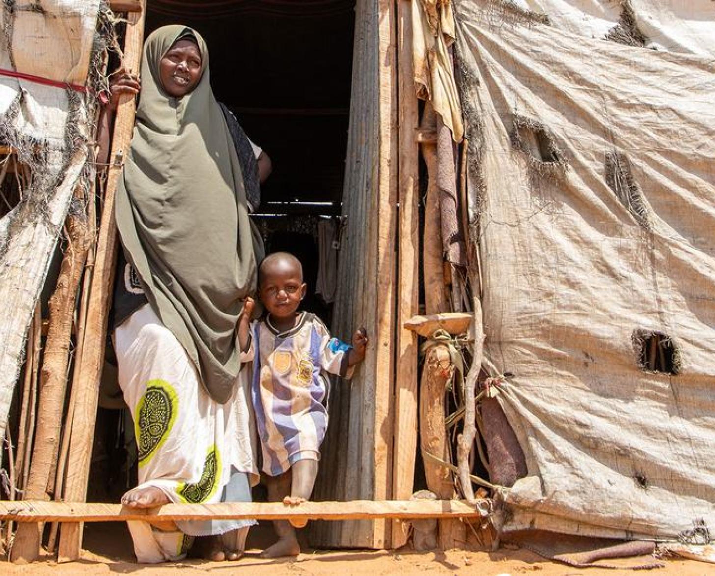 Женщина с маленьким ребенком стоят в проеме двери