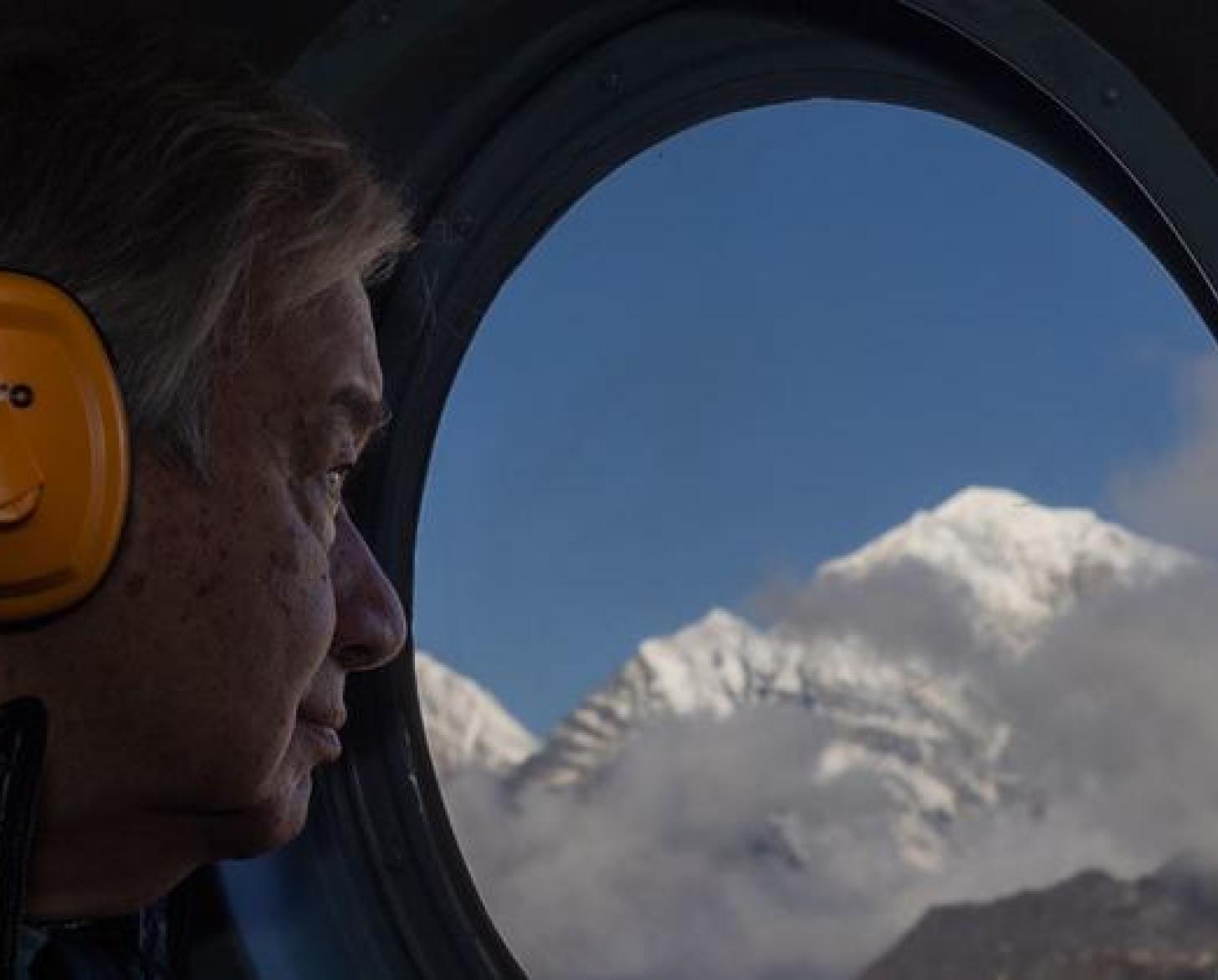 Антониу Гутьериш в профиль смотрит в иллюминатор на горы Непала