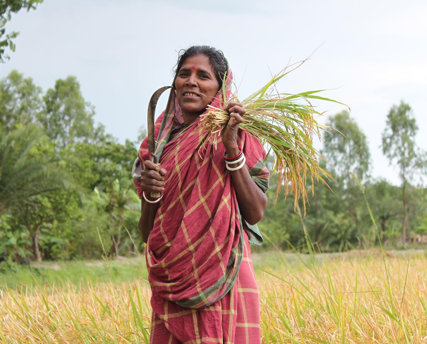 woman standing in a field holding a knife for cutting plants