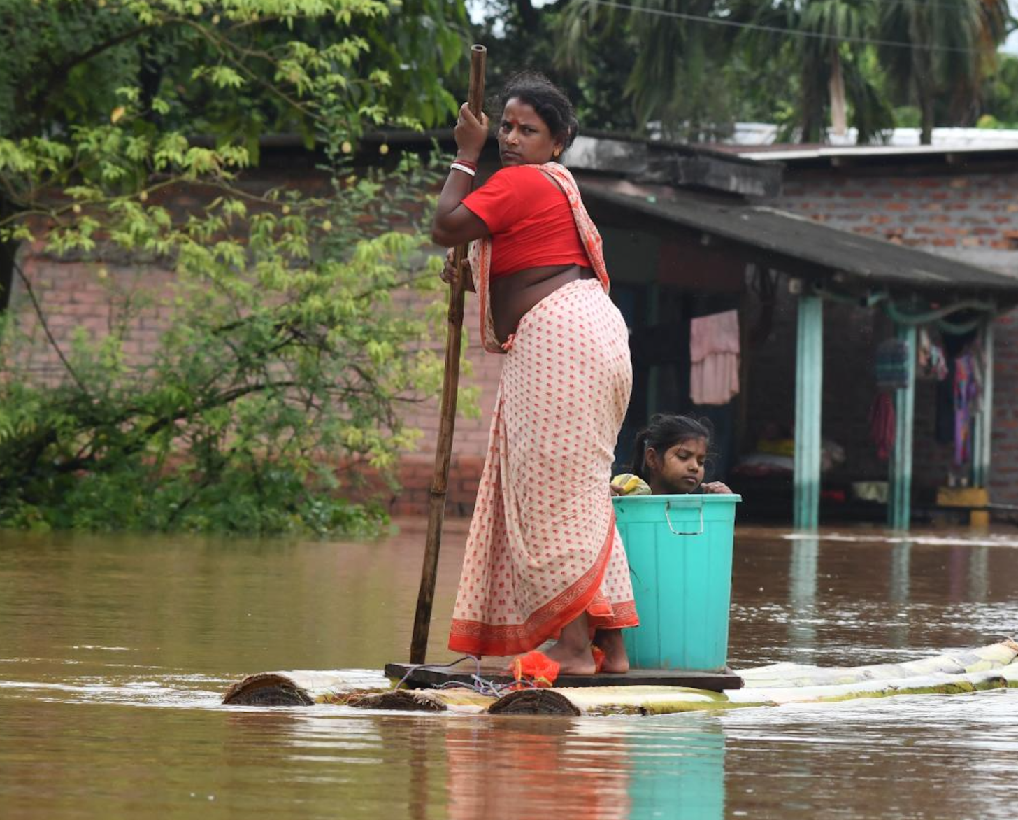 woman paddles a make-shift raft down a flooded street