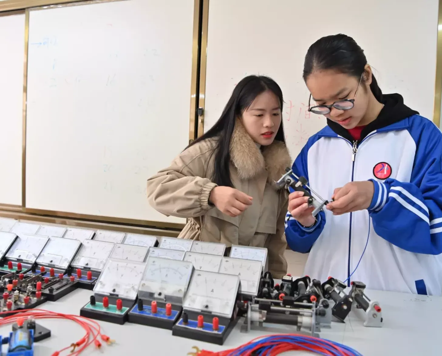 广西天等县华隆中学学生韦李敏（右）和老师刘玉萍在做电阻实验（2023年12月27日摄）。